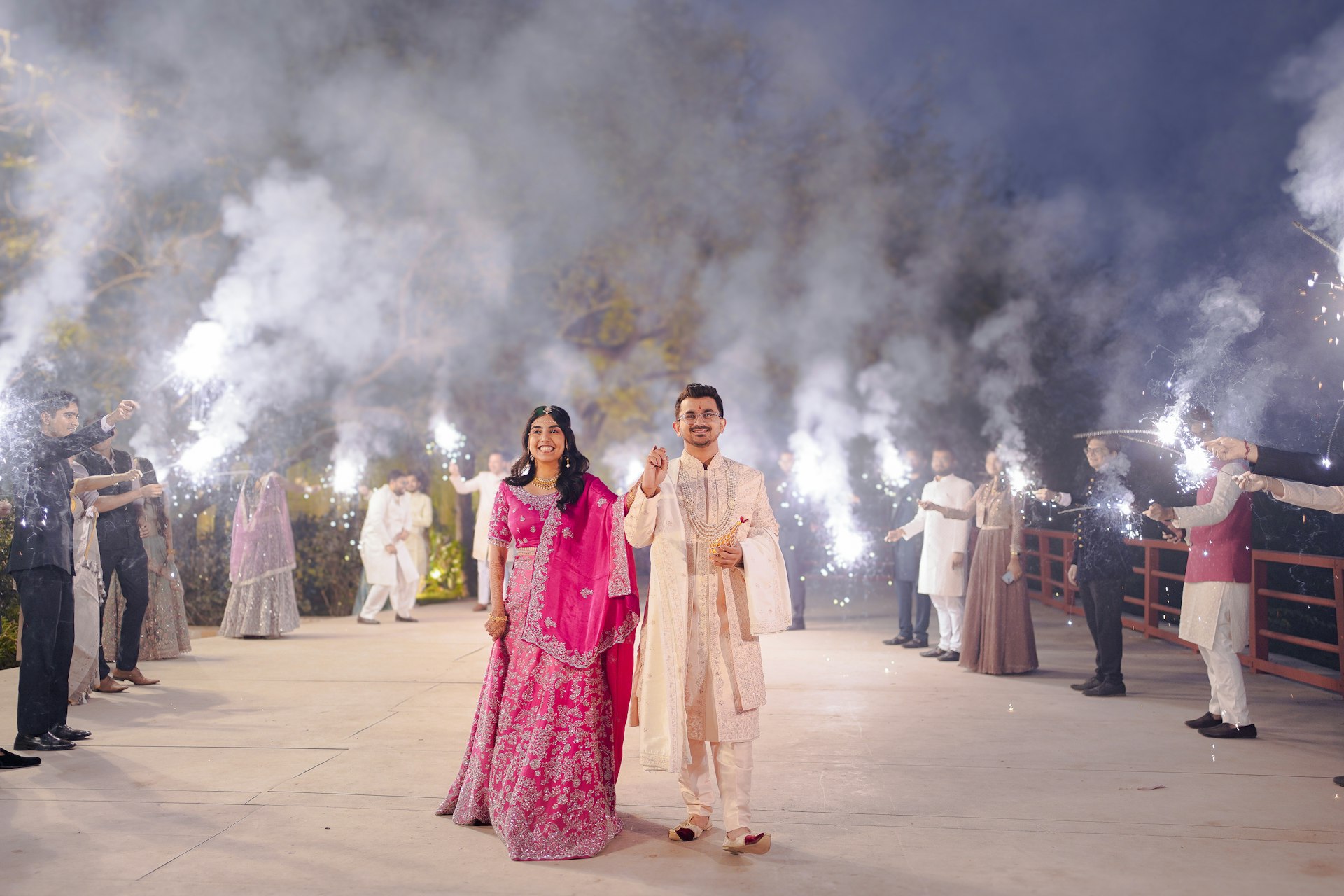 Bride and groom walk through a smoke-filled entrance.
